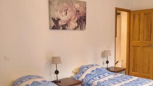 Een slaapkamer met twee bedden, een houten deur en een schilderij aan de muur.