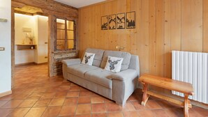 A cozy room with a sofa, a wooden bench, and a radiator. - Apartment 'Fior Di Montagna' with Mountain View, Shared Terrace and Wi-Fi (Bormio)