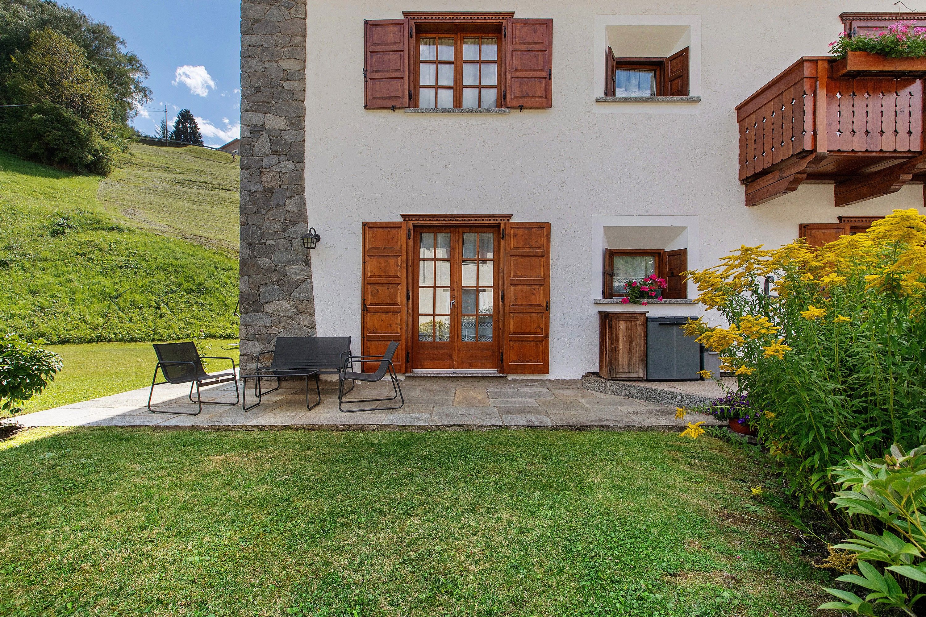 Un bâtiment à deux étages avec une façade en pierre, des volets en bois et un petit balcon.