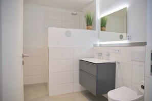 Une salle de bain moderne équipée d’une douche, de toilettes et d’un lavabo.