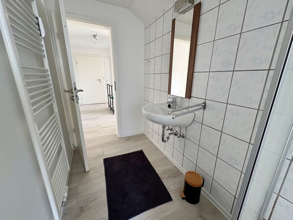 A modern bathroom with a white sink, mirror, and tiled walls.
