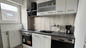 Una cocina compacta equipada con horno empotrado, lavavajillas y cafetera.