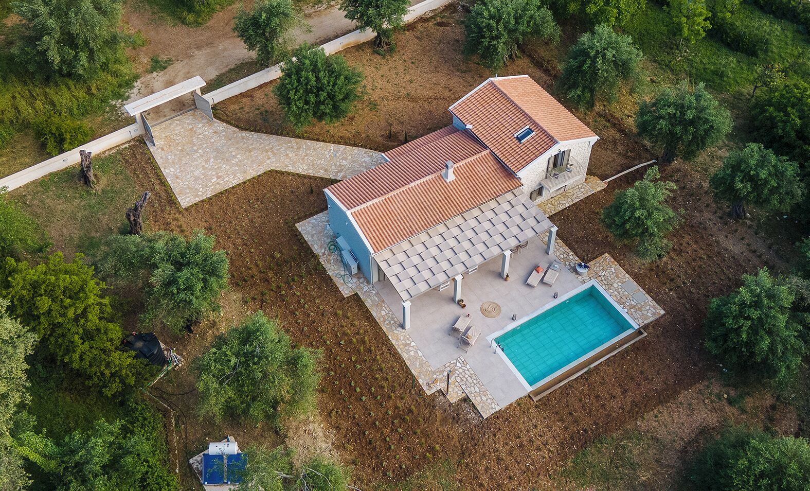 Una casa de dos pisos con piscina, mobiliario exterior y un camino de piedra.