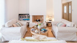 Ein geräumiges Wohnzimmer mit hohen Decken, einem Kamin und einem Fernseher.