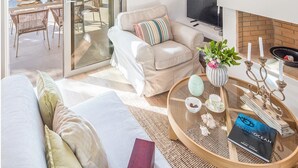 Ein modernes Wohnzimmer mit Sofa, Glastisch, Fernseher und Kamin.