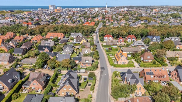 An aerial view of a residential area with houses, roads, and a distant view of a city skyline. - Tinkas Kate - Charming bungalow with a garden in Westerland, Sylt (Sylt)