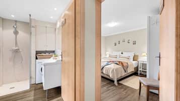 Ein modernes Hotelzimmer mit Dusche, einem Bett, einem Schreibtisch und einem Stuhl.