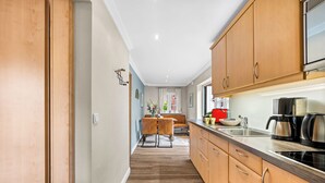 A modern kitchen with wooden cabinets, a stainless steel sink, and a black stove. - Tinkas Kate - Charming bungalow with garden in Westerland, Sylt (Sylt)