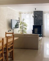 Una sala de estar con un sofá, televisor, chimenea y una planta.
