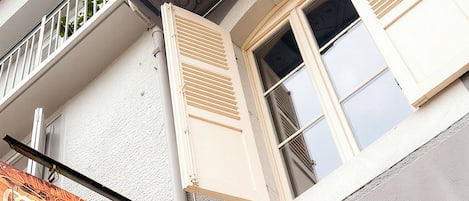 Um edifício com uma placa que diz "Chambres d'hôtes" e uma janela com persianas.