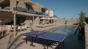 Edificio de piedra con piscina, mobiliario exterior y mesa de ping pong.