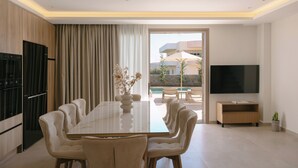 Un comedor moderno con una mesa grande, sillas cómodas, un televisor de pantalla plana y vistas al área de la piscina.