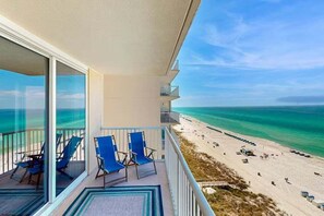 Ein Balkon mit blauen Stühlen mit Blick auf einen Strand.