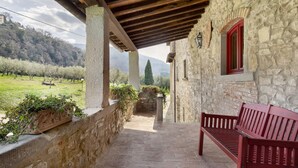 A stone building with a wooden pergola, a bench, and a view of a green landscape. - Il Focolare – Spacious Apartment in Farmhouse with Private Terrace and Pool (Pelago)