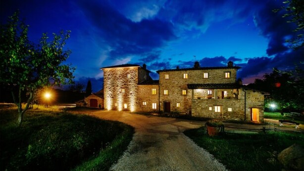 A stone building with multiple windows and a central tower, surrounded by a gravel path and greenery. - Il Focolare – Spacious Apartment in Farmhouse with Private Terrace and Pool (Pelago)