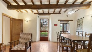 A dining area with a wooden table and chairs, a striped chair, and a door leading outside. - Agriturismo Palaia - Le Botti Spacious Apartment in Farmhouse with Pool (Pelago)