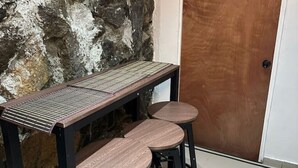 A table with a metal frame and a wooden top, accompanied by three stools with metal legs.