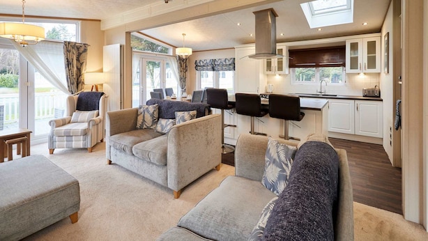 A spacious living room with a large sofa set, a dining area, and a kitchen with white cabinets and a skylight. - Host Stay Sutton Lodge (York)