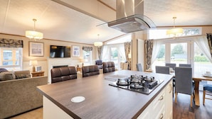 A modern kitchen with a central island, dining area, and seating. - Host Stay Sutton Lodge (York)