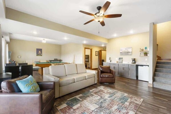 A spacious living area with a sofa, a coffee table, and a ceiling fan. There is a kitchen area with cabinets and a countertop. - Hooked on Branson Cove - Pool Hot Tub Fireplace (Hollister)