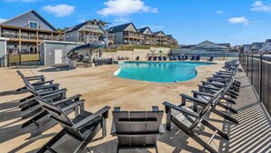 A swimming pool with lounge chairs and a slide, surrounded by buildings with balconies. - Hooked on Branson Cove - Pool Hot Tub Fireplace (Hollister)