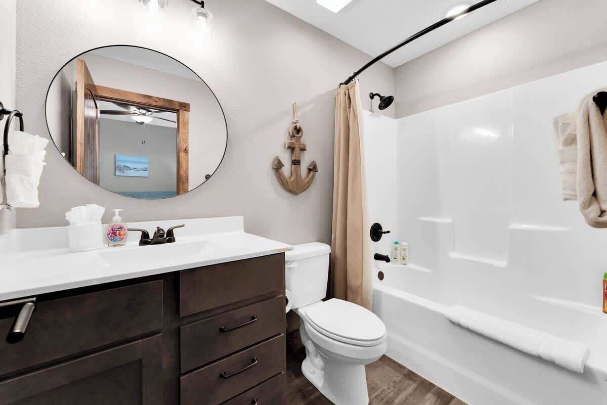 Une salle de bain moderne avec un lavabo blanc, un meuble-lavabo en bois foncé, des toilettes blanches et une baignoire blanche.