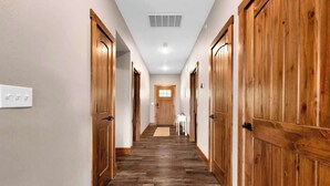 A hallway with wooden doors, a white wall, and a wooden floor. - Hooked on Branson Cove - Pool Hot Tub Fireplace (Hollister)