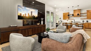 A modern living room with a flat-screen TV, a sofa, and a coffee table. - Austin Family Retreat at Ember House (Austin)