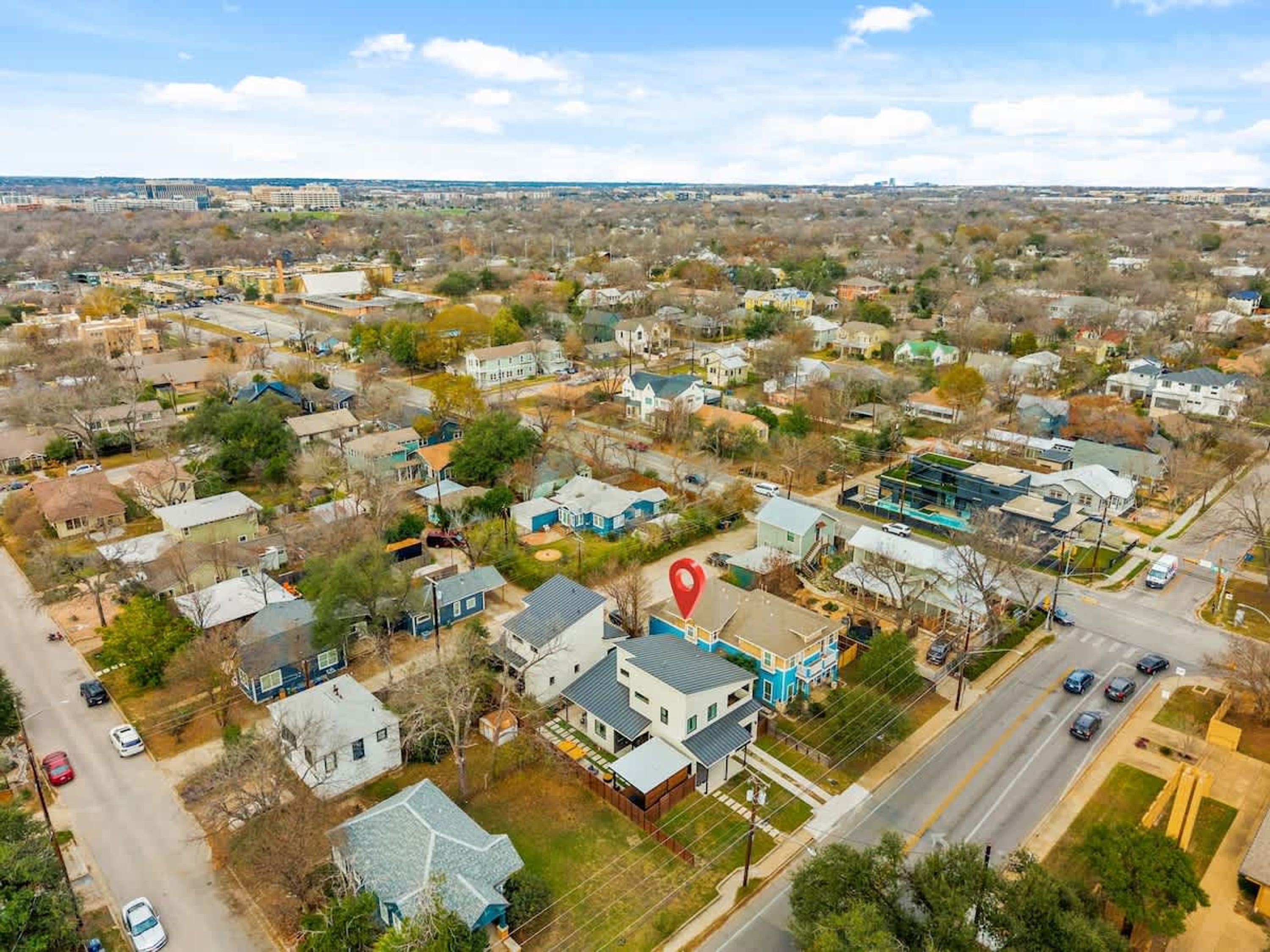 Vue aérienne d’un quartier résidentiel avec des maisons, des routes et un marqueur de localisation rouge.