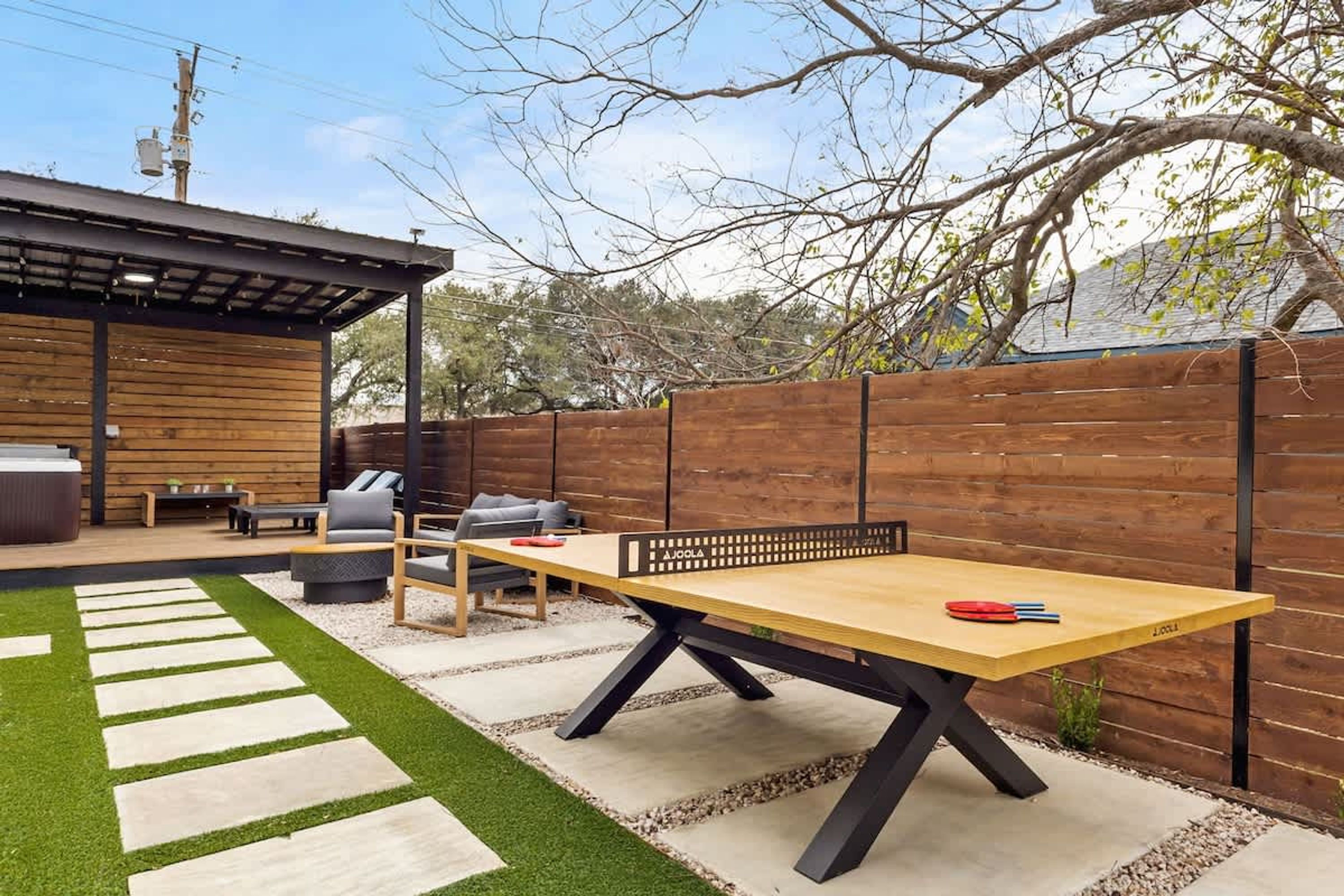Eine Terrasse mit einem Tischtennisplatte, Sitzgelegenheiten im Freien und einem Holzdeck.