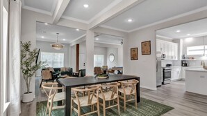 Een ruime woonruimte met open plattegrond, met een eettafel en stoelen, een keuken en een zithoek met een bank en salontafel.