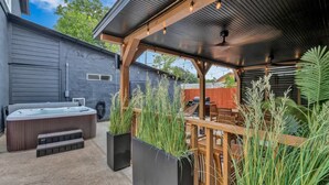 Een achtertuin met een jacuzzi, houten terras en zitgedeelte.