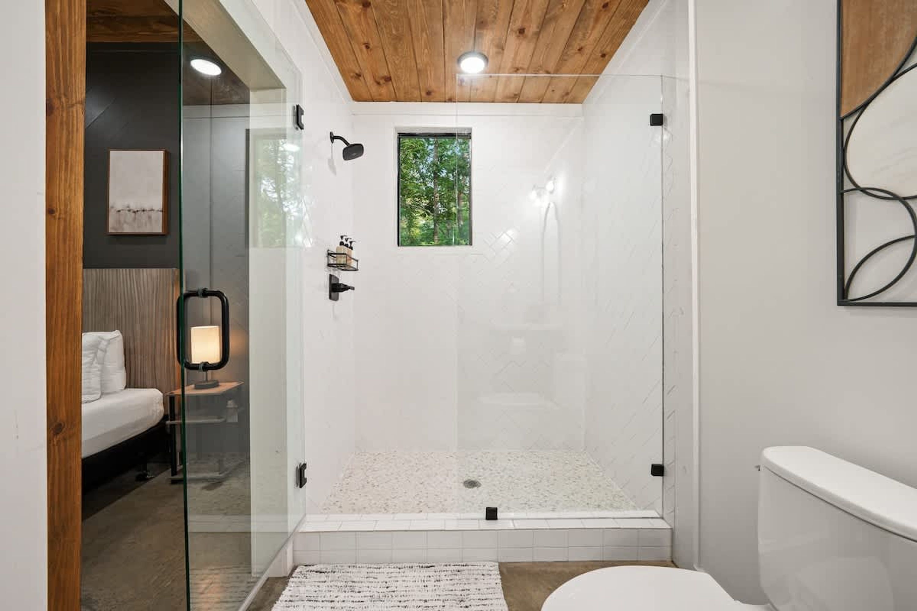 A modern bathroom with a glass-enclosed shower, a white toilet, and a wooden ceiling.