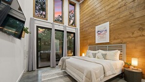 A bedroom with a large bed, a TV mounted on the wall, and a wooden ceiling. - Hgtv Cabin- 2 Private Acres -patio Oasis Dogs OK (Broken Bow)