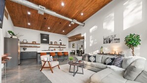 A spacious living area with a high ceiling, a kitchen in the background, and a dining area with orange chairs. - Hgtv Cabin- 2 Private Acres -patio Oasis Dogs OK (Broken Bow)