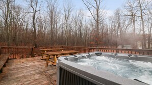 Un jacuzzi en una terraza de madera rodeado de árboles.