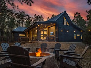 A cabin with a fire pit and outdoor seating, surrounded by trees. - Cabin - Near Black Mountain (Broken Bow)