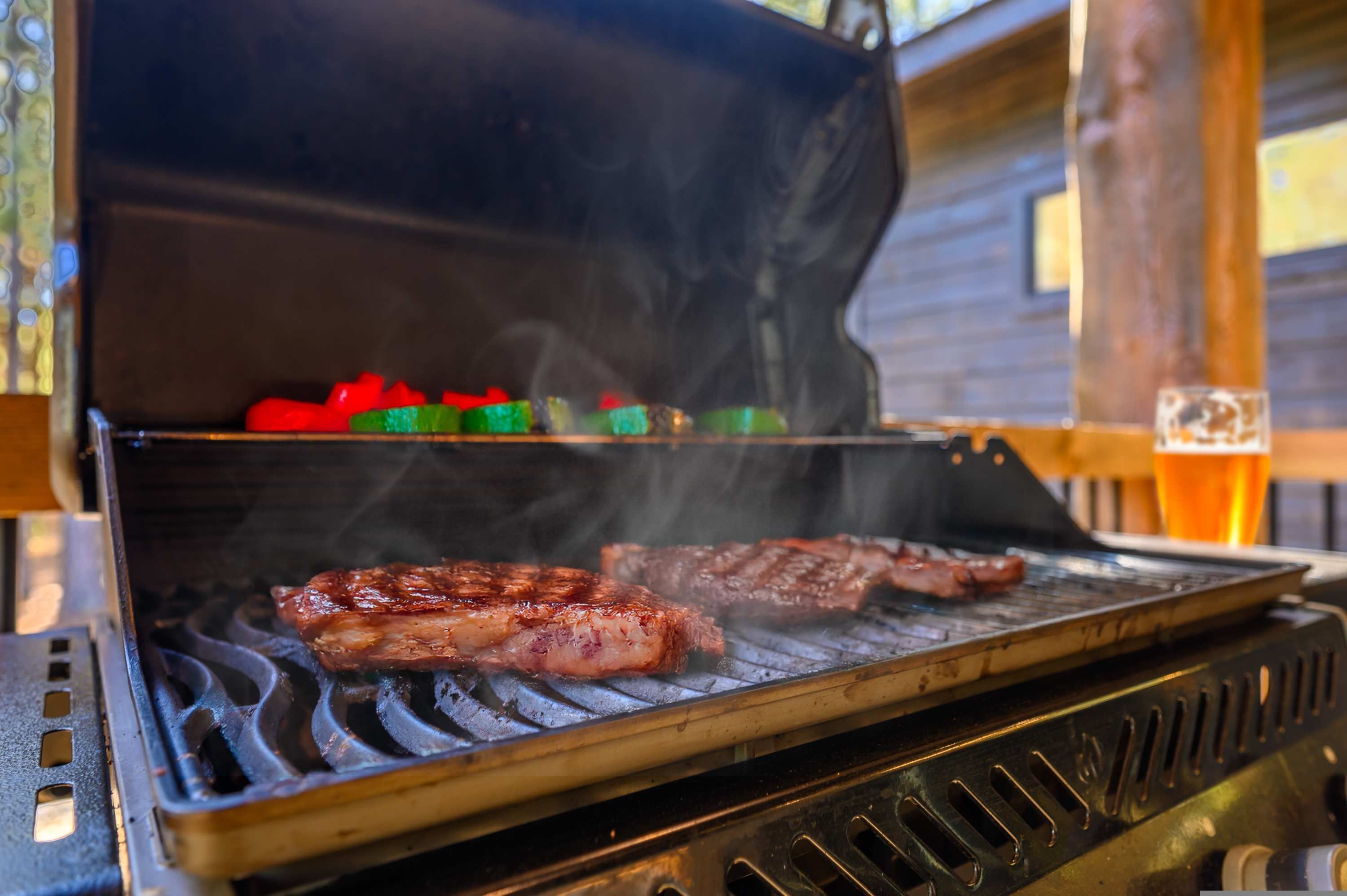 A grill with steaks and vegetables being cooked.