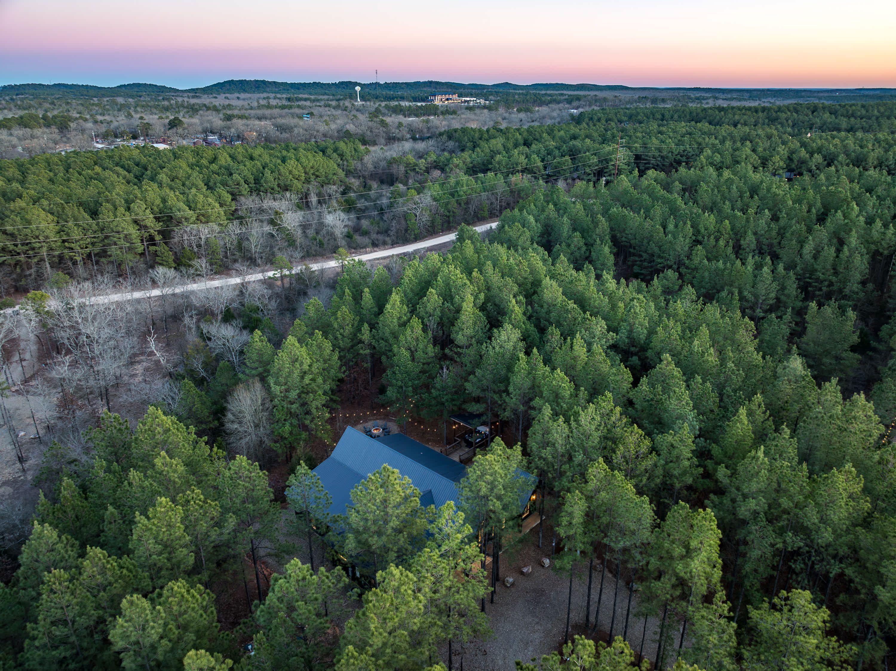 An aerial view of a forested area with a cabin surrounded by dense trees.
