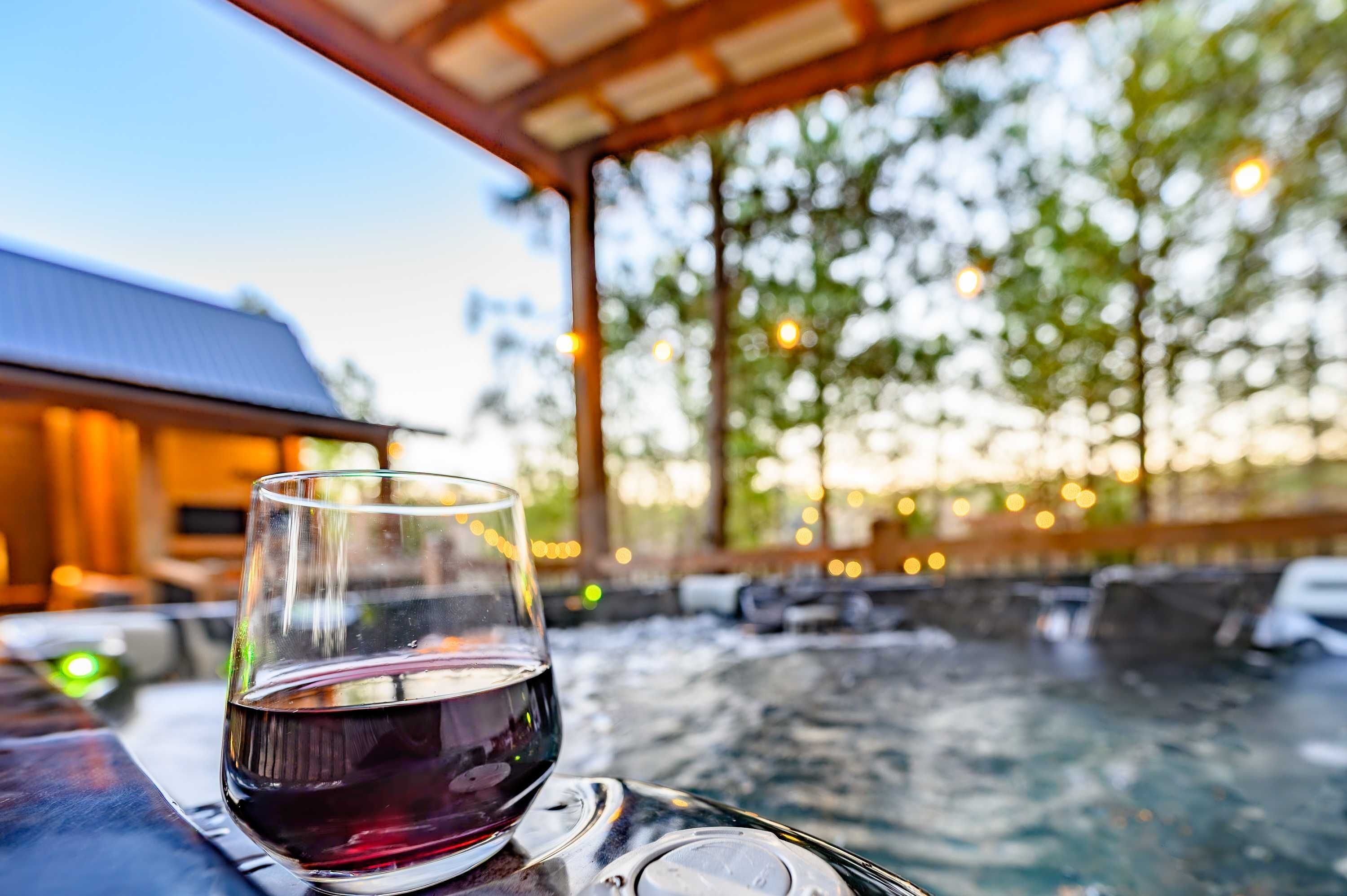 Una copa de vino tinto sobre una mesa, con un jacuzzi al fondo.