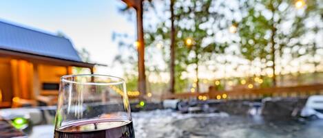 Una copa de vino tinto sobre una mesa, con un jacuzzi al fondo.