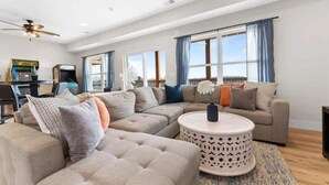 A spacious living room with a sectional sofa, a round coffee table, and a ceiling fan. - Modern Getaway w Hot Tub Arcade Stunning Views (Branson)