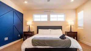 A bedroom with a bed, two bedside lamps, a blue accent wall, and two windows. - Elegant Spacious 4BR Home Peyton (Elbert)