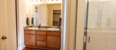 Un baño con muebles de madera, un lavabo doble y una cabina de ducha de vidrio.