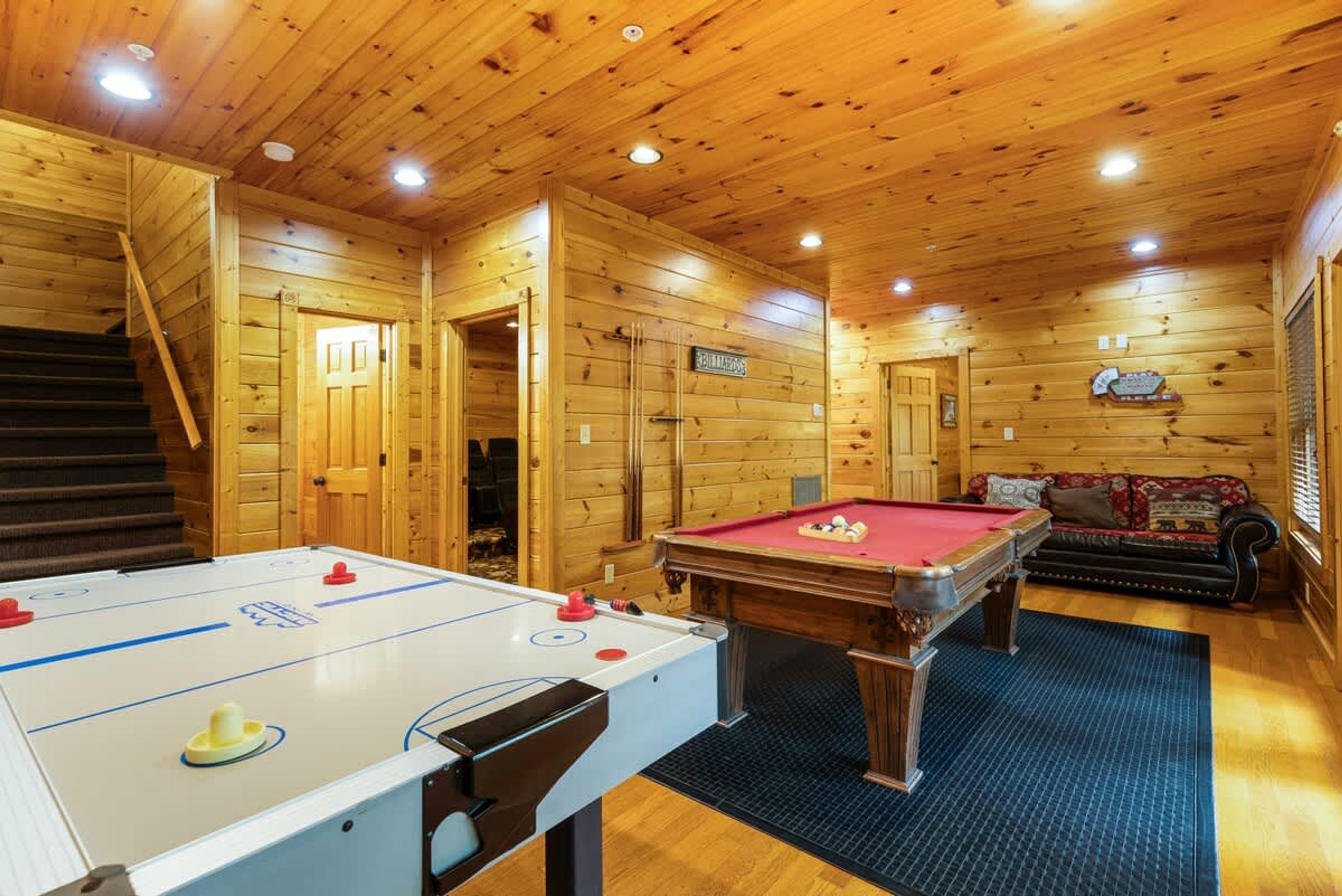 Un interior de madera con mesa de billar, mesa de fútbolín y un sofá.