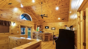 Ein Holzblockhaus-Interieur mit Essbereich, Bar und Deckenventilator.