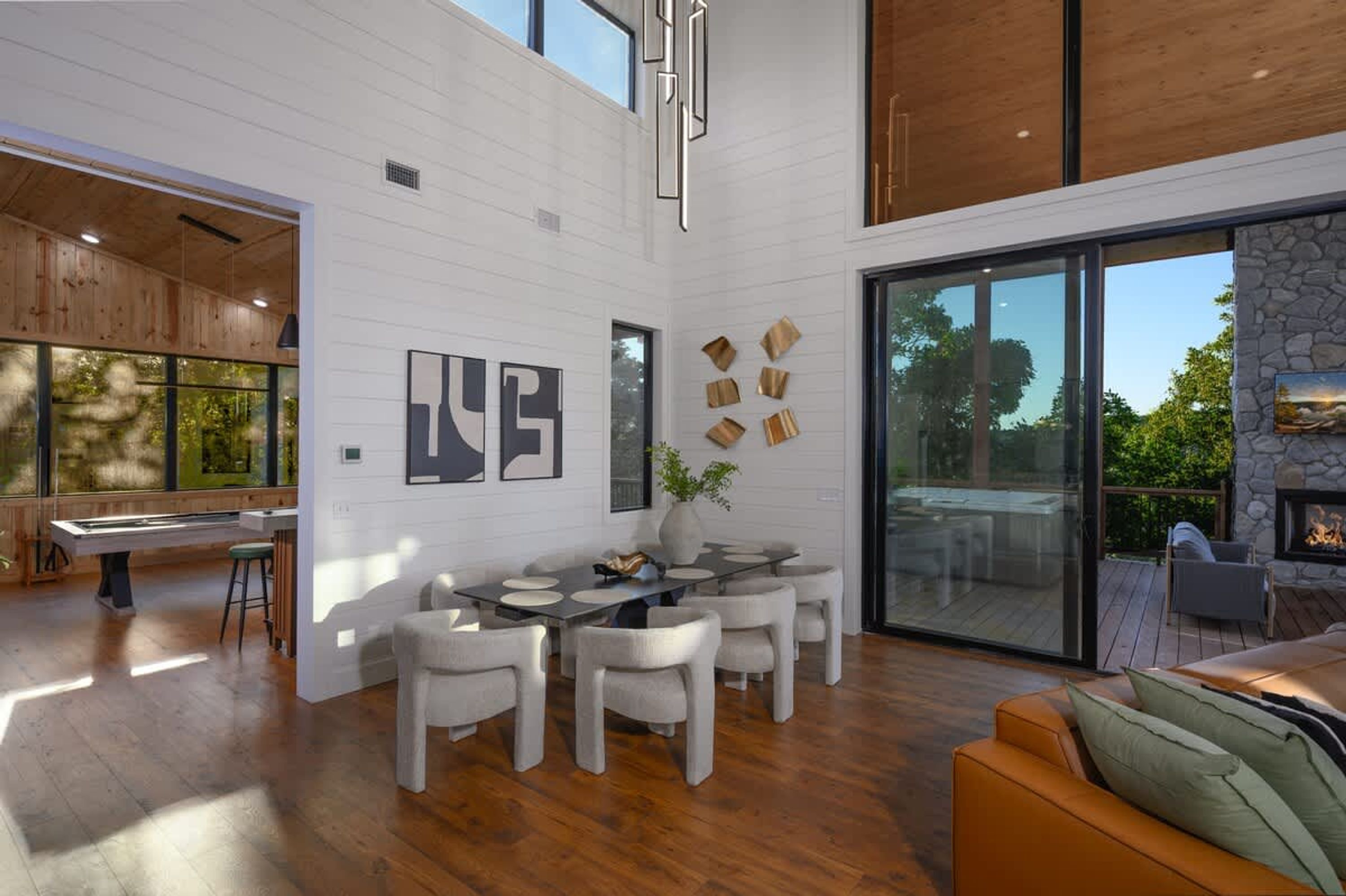 A spacious interior with a dining area, a fireplace, and large windows offering a view of the outdoors.