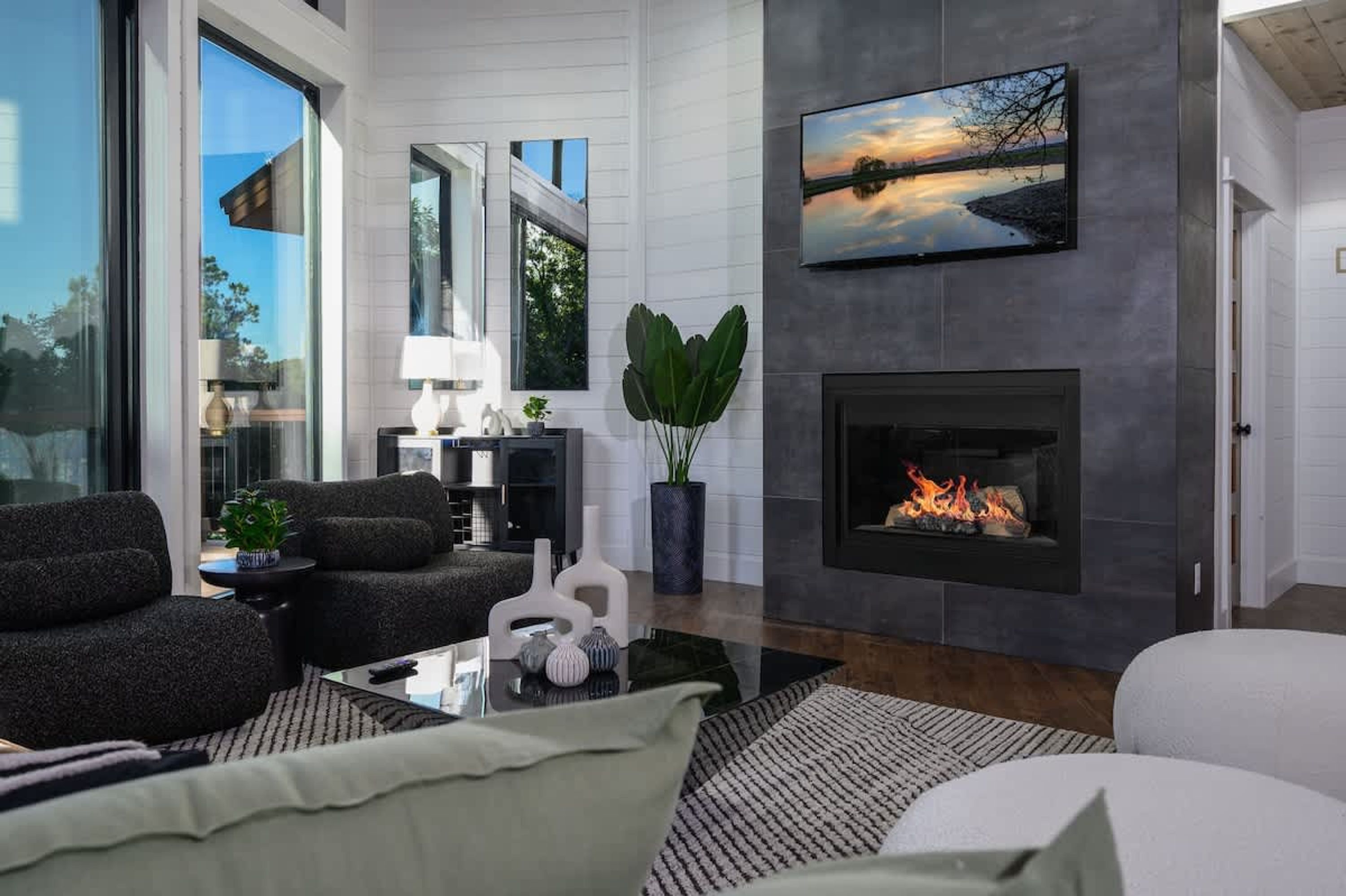 A modern living room with a fireplace, comfortable seating, and a large window offering a view of the outdoors.