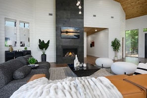 A modern living room with a fireplace, a large mirror, and a cozy seating area. - Sit n Go Family Retreat Poker Darts Billiards (Broken Bow)