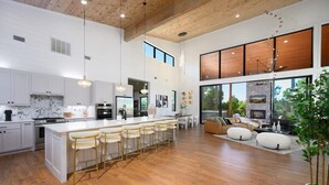 A spacious kitchen with a large island, bar stools, and a dining area with a fireplace. - Sit n Go Family Retreat Poker Darts Billiards (Broken Bow)